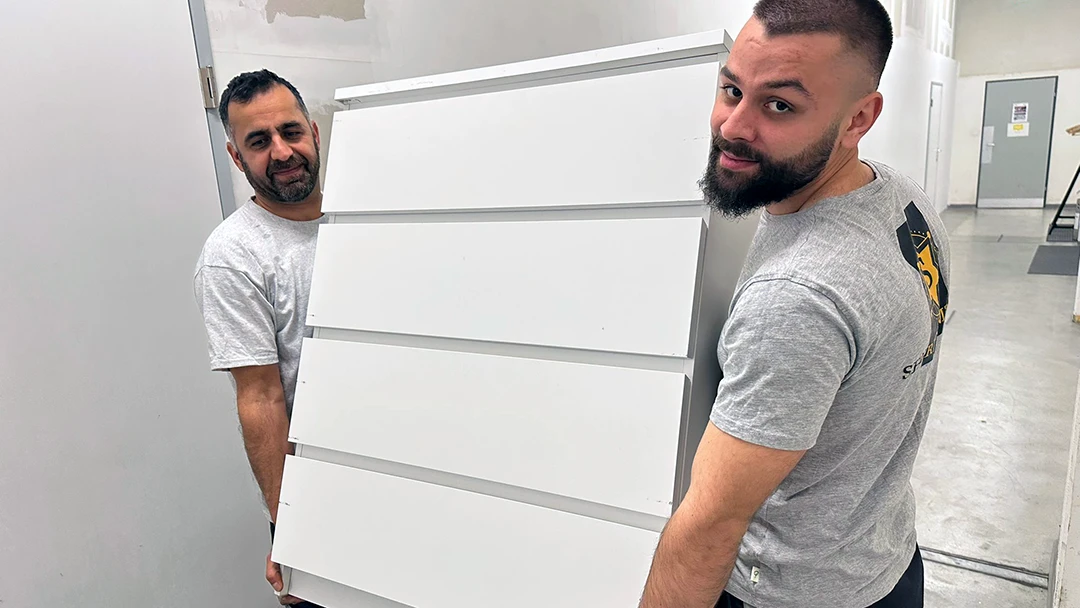 Mitarbeiter von Sheriff Umzüge tragen eine Kommode