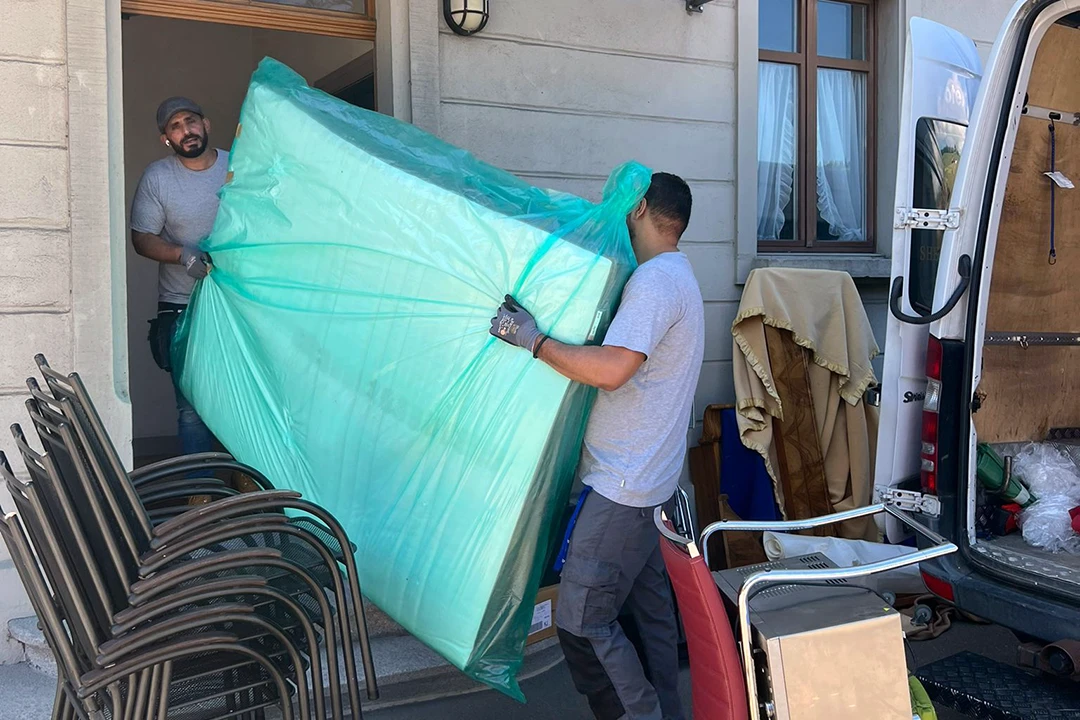 Mitarbeiter von Sheriff Umzüge tragen eine sorgsam eingepackte Matratze aus einem Hauseingang